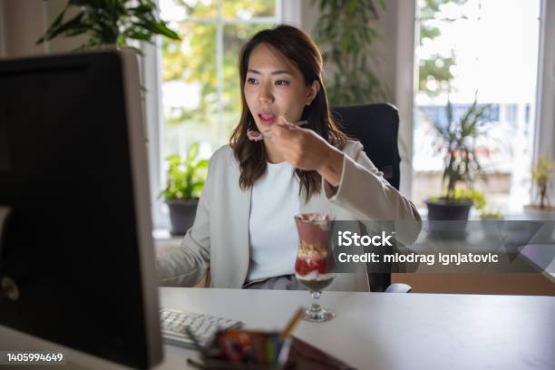 チア/シリアルプリンを食べながらホームオフィスからコンピューターで作業する日本人女性