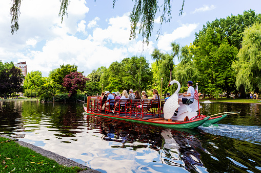 Boston, Massachusetts, USA - June 28, 2022: Swan boat full of people traveling on the Boston Public Garden pond