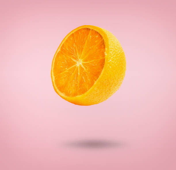istock Flying half orange fruit at pink background with shadow. 1405994998