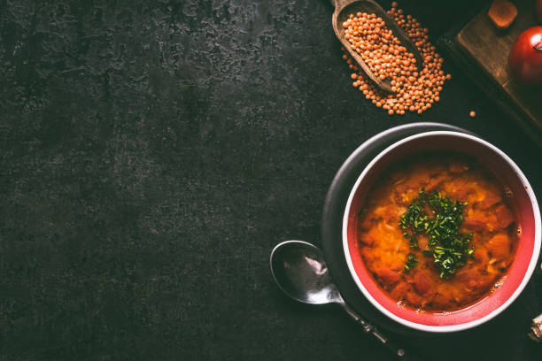 Red lentil soup with spoon in bowl on dark rustic background , top view with copy space.