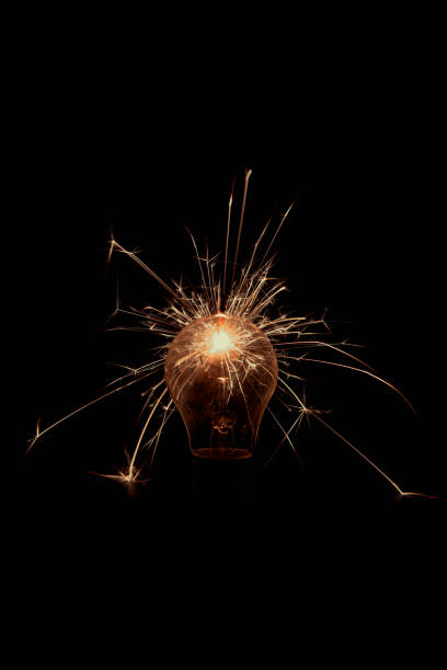 istock Incandescent lamp with sparks on a black background. 1405996003