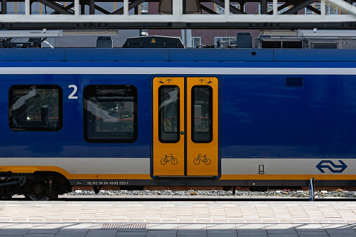 Hengelo, Twente, Overijssel, Netherlands, april 11th 2022, Dutch yellow/blue electric NS train type 'Sprinter' moving past at Central railroad station Hengelo, Overijssel - the Hengelo municipality has a population of 82.000 (2022), the Central station was opened in 1865