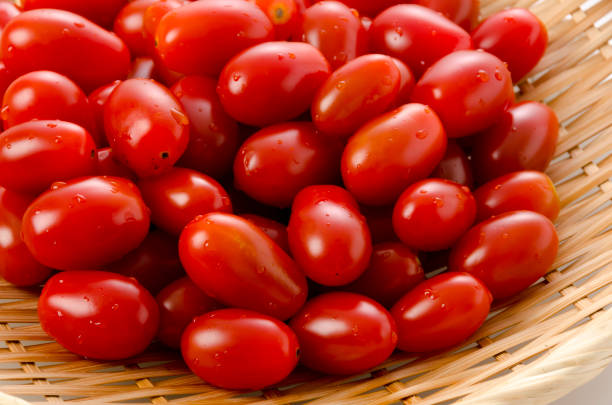 Fresh cherry tomatoes on bamboo sieve on white background Fresh cherry tomatoes on bamboo sieve on white background grape tomato stock pictures, royalty-free photos & images