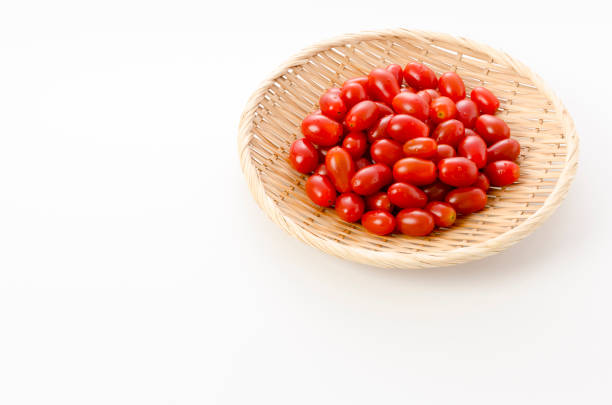 Fresh cherry tomatoes on bamboo sieve on white background