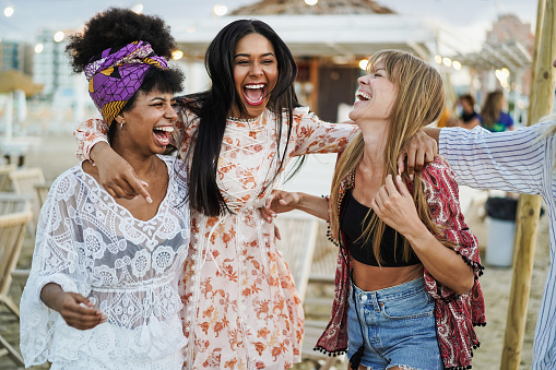 Multiracial happy friends having fun outdoor at beach party - Soft focus on right girl pants