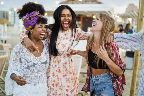 Multiracial happy friends having fun outdoor at beach party - Soft focus on right girl pants