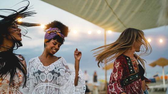 Amigos multirraciales divirtiéndose bailando juntos al aire libre en la fiesta en la playa - Enfoque suave en la cara izquierda de la chica photo