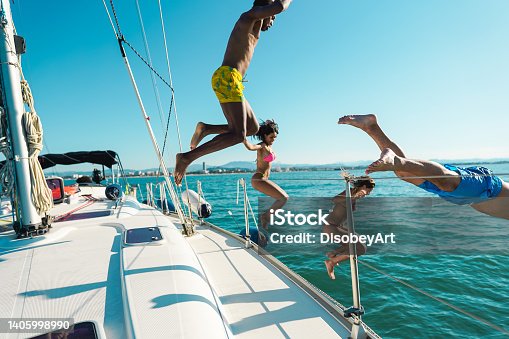istock Happy friends diving from sailing boat into the sea - Focus on left girl face right man face 1405998990