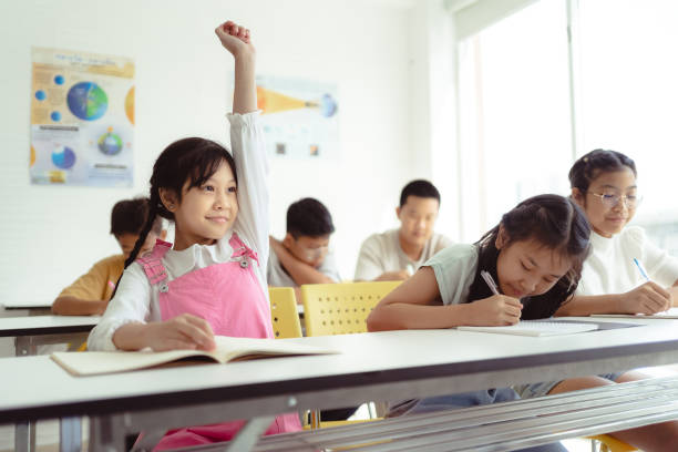 A student raising their hand in a classroom in Bangkok, Thailand.