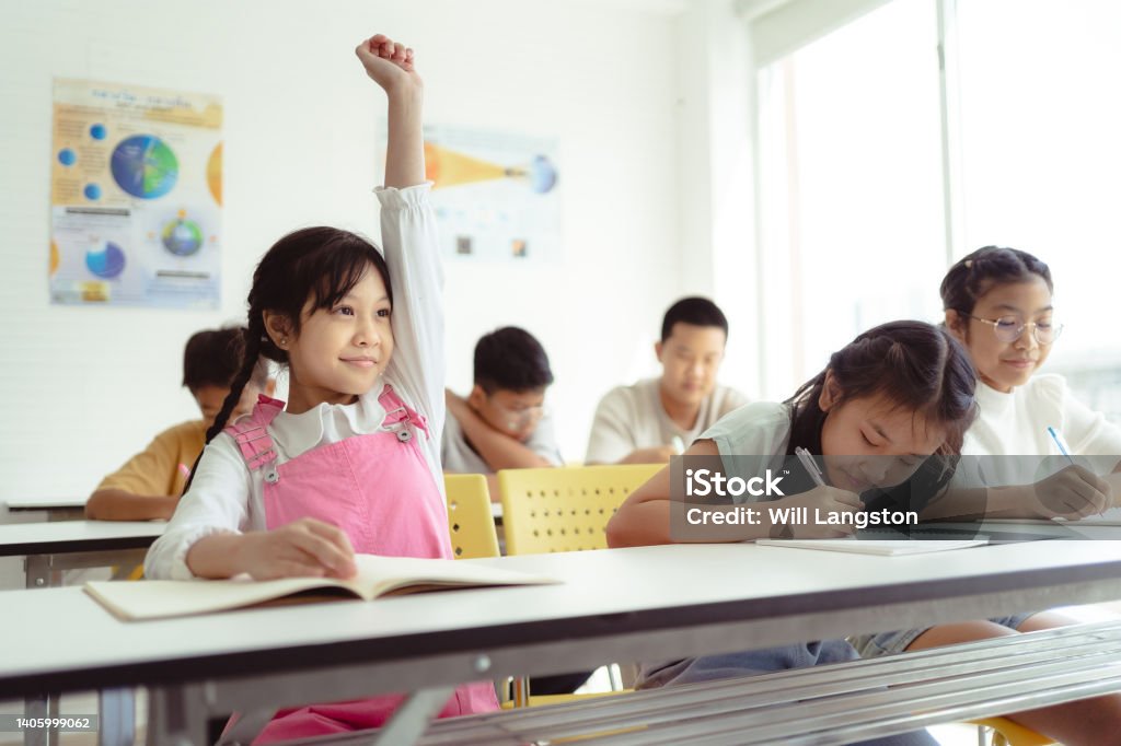 Student Raising Hand in Classroom Learning Bangkok, Thailand A student raising their hand in a classroom in Bangkok, Thailand. Classroom Stock Photo