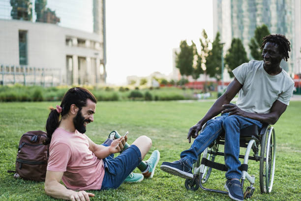 istock Multiracial friends with disability having fun using mobile phone at park city - Focus on african man sitting on wheelchair 1405999450