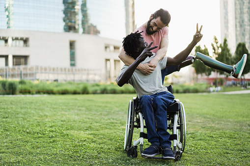 Amigos felices con discapacidad divirtiéndose en park city - Enfoque en la mano izquierda del hombre africano photo