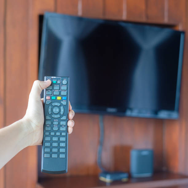 istock hand using remote controller for adjust Smart TV inside the modern room at home or luxury hotel 1405999462