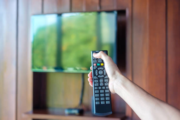 istock hand using remote controller for adjust Smart TV inside the modern room at home or luxury hotel 1405999579