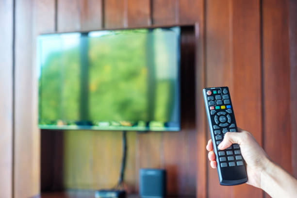istock hand using remote controller for adjust Smart TV inside the modern room at home or luxury hotel 1405999769