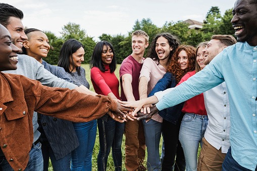 Young diverse team having fun stacking hands outdoor - Focus on hands