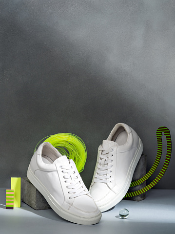 Stylish women's white sneakers on podium. Trendy female accessories. Conceptual still life of footwear. Shoes fashion photography. Minimalist fashion creative concept.