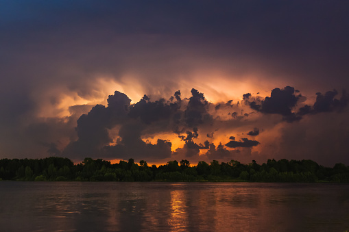 Flash of lightning in reflection of river. Natural disaster. Night dark dramatic sky. Scary cloud. Dangerous heaven. Storm weather. Summer rain. Nature background. Rainy season. Mystical landscape