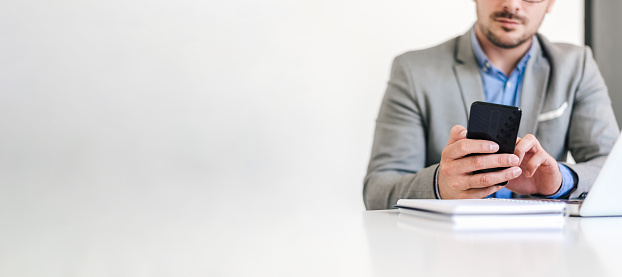 Businessman wearing formals text messaging on mobile phone while sitting at office desk