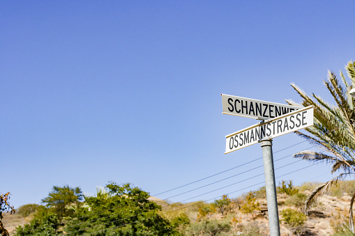 This street may have been named for Carl Adolf Erwin Ossmann, an impressionist and modern artist born in 1883 and who died in 1935. He was active in and lived in Namibia.