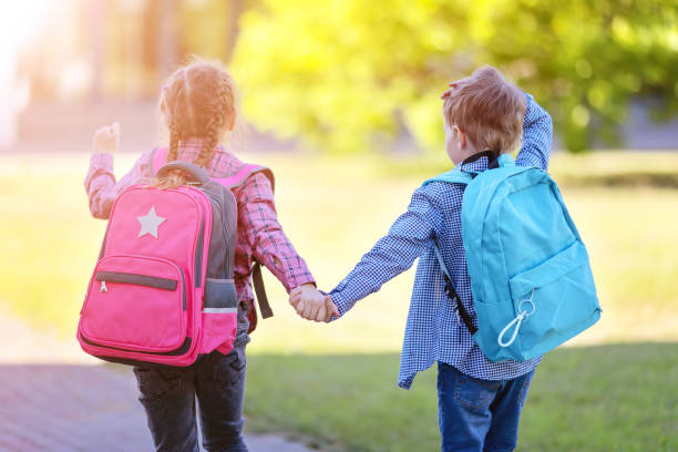 istock Girl and boy going to the school holding hands to study at it. 1406009650