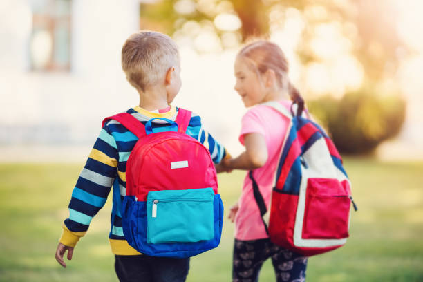 istock Girl and boy going to the school holding hands to study at it. 1406009713