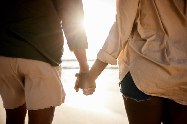 istock Young couple holding hands on a beach at sunset 1406012301