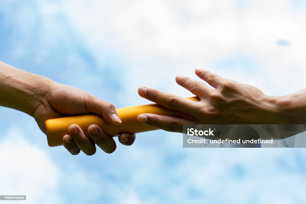 Close up hand set baton from hand to hand on sky background. Business concept for teamwork and team builder. Relay Baton Stock Photo