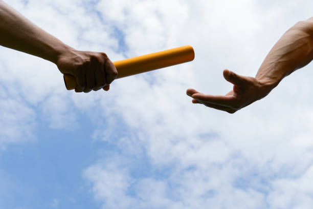 istock Close up hand set baton from hand to hand on sky background. Business concept for teamwork and team builder. 1406012471