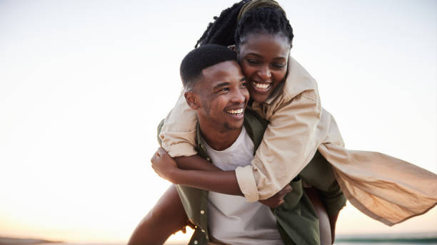 istock Laughing young man carrying his girlfriend on his back at the beach 1406013581