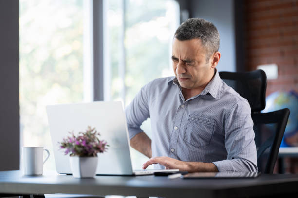 Businessman Having Spine Ache Due To Work Overload And Bad Posture stock photo