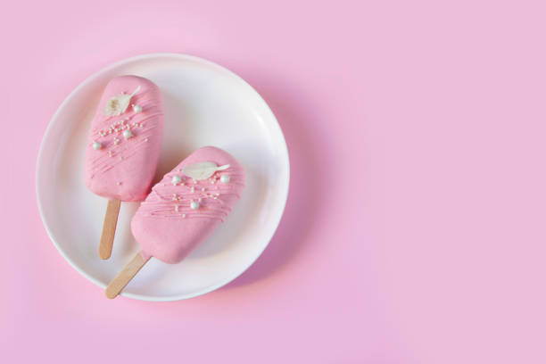Eskimo cake. Ice cream sweet eskimo with pink chocolate icing. Chocolate covered ice cream on stick, pink background. Sweets background, sweet price concept, Ice cream template, summer sale layout.