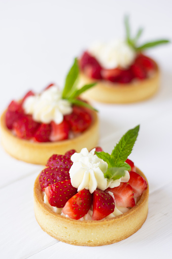Mini tarts with fresh strawberries, wiped cream and mint leaves. Strawberry tarts