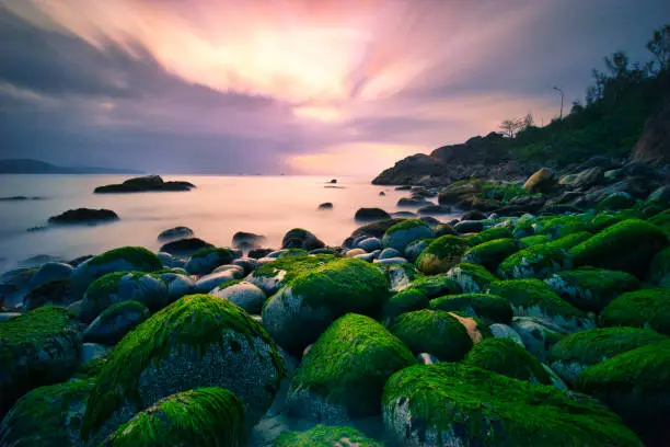Long exposure image of dramatic sky seascape with mossy rocks in background of sunrise - sunset landscape Amazing light Binh Dinh natural landscape