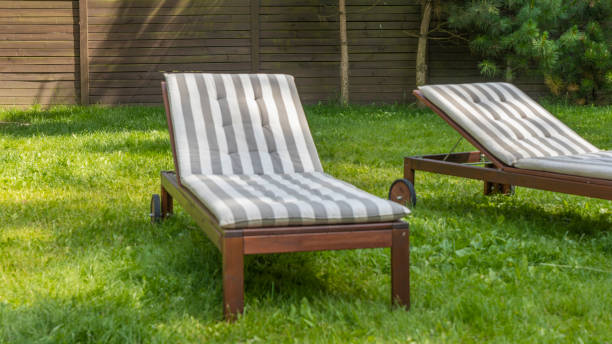 istock Lounge chairs on the backyard in a beautiful garden. Two empty sunbeds on the grass. 1406019994