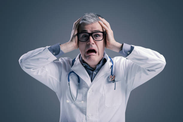 Panicked doctor with head in hands stock photo
