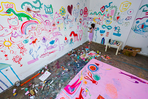 Little girl paints a mural on the wall