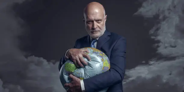 Photo of Greedy corporate businessman crushing and exploiting earth