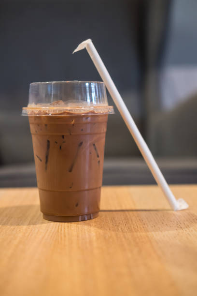 Iced chocolate in glass with straw on wood table.