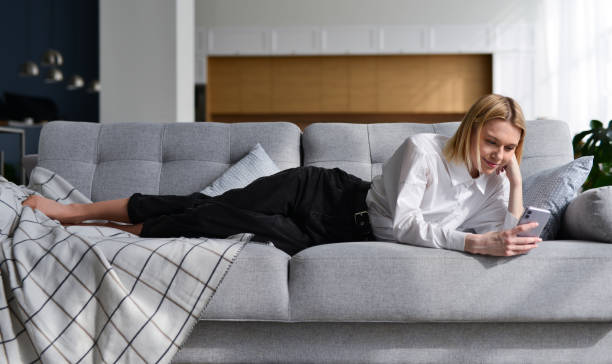 istock Woman with smartphone at home lying on sofa. 1406022509