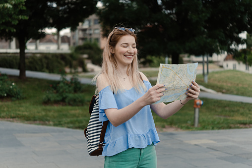 Portrait of a beautiful, young female tourist using a city map and exploring the city