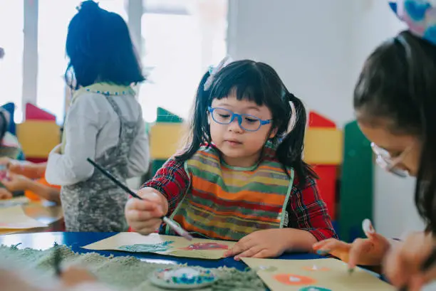 Eurasian Montessori preschool student enjoying drawing in classroom