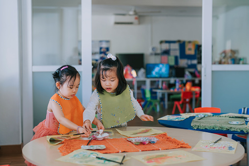 2 asian chinese Montessori preschool girls enjoying drawing in classroom
