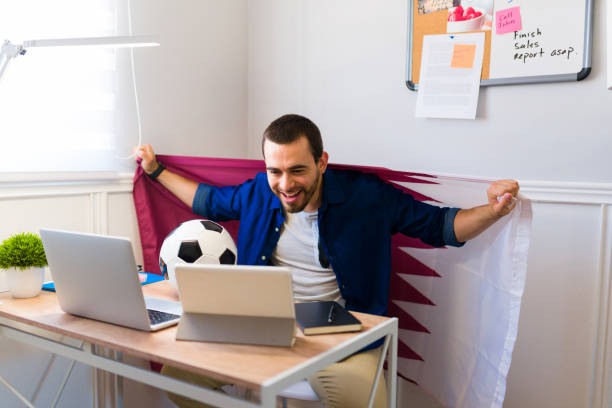 istock Young man doing freelance work at home and watching the soccer game 1406032909