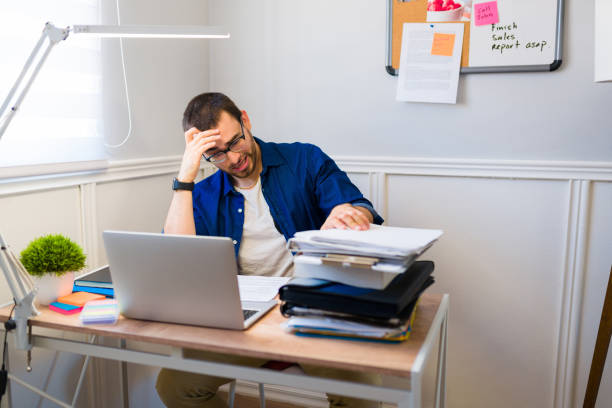 istock Tired man feeling overwhelmed while sitting at his work desk at home 1406032979