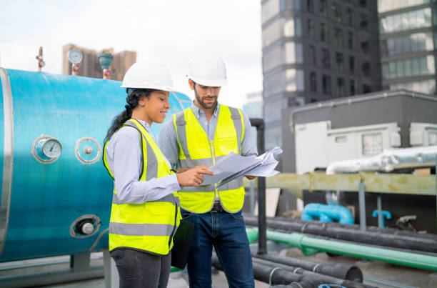 istock Couple professional engineer or technician workers discuss with blue print of construction site and stay near tank on deck of building. 1406033367