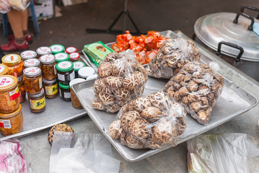 Bangkok, Thailand - October 23, 2012. Local people and tourists buy food on street market. Mushrooms and canned food on stall.