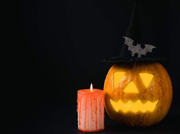 istock Halloween pumpkin on brown wood texture with candles. Composition on a dark background. Scary composition with glowing eyes and mouth. Holiday concept. copy space 1406035712