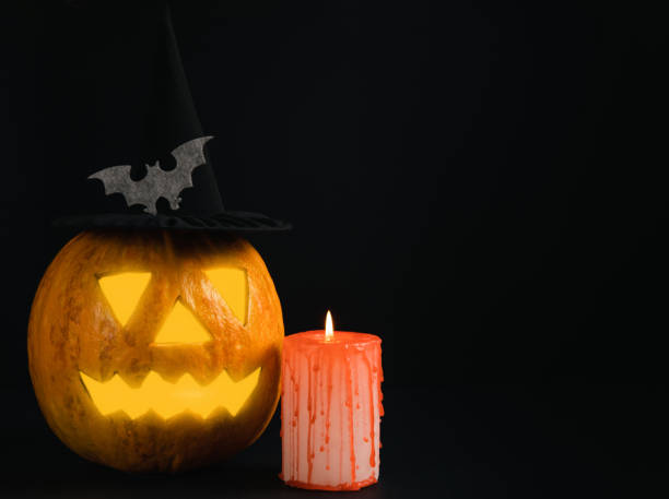 istock Halloween pumpkin on brown wood texture with candles. Composition on a dark background. Scary composition with glowing eyes and mouth. Holiday concept. copy space 1406035748