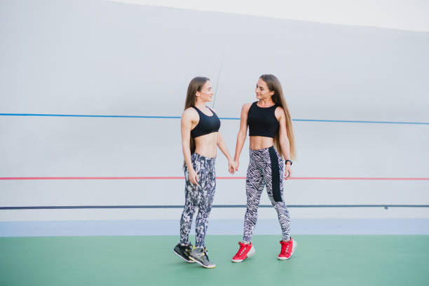 sports and fitness outside the gym. young fit women with perfect bodies in sportswear train together outdoors on the playground. - playing field effort outdoors human age imagens e fotografias de stock